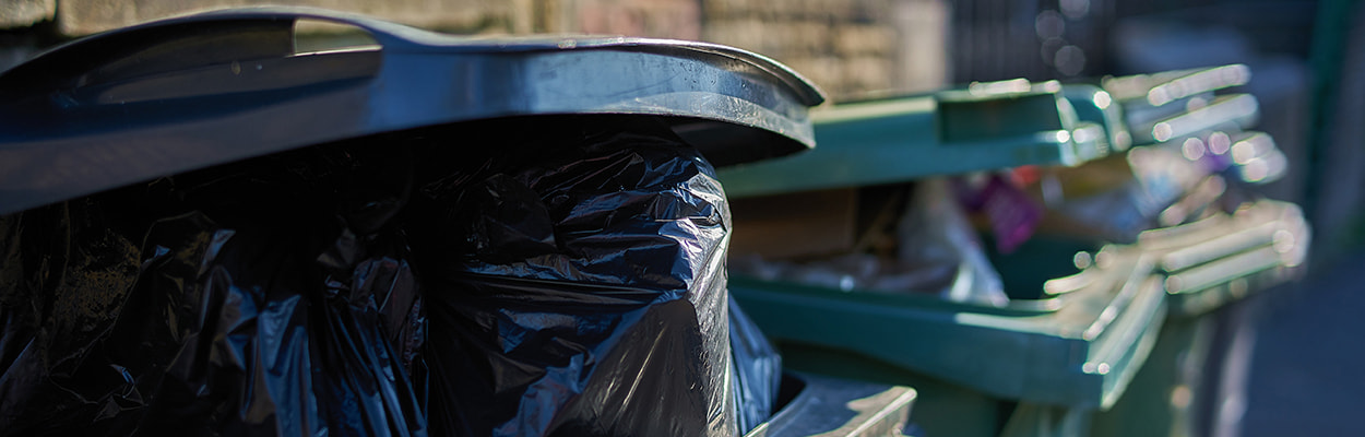 Line of waste bins full of rubbish